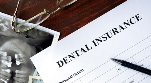 Top of dental insurance form with X-ray, glasses, and pen