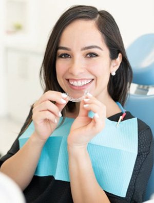 a patient smiling while holding clear aligners