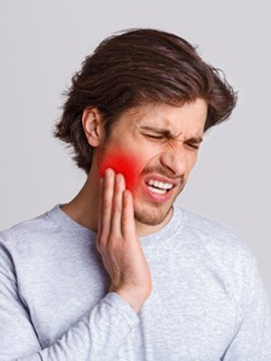 a man holding his cheek due to tooth pain