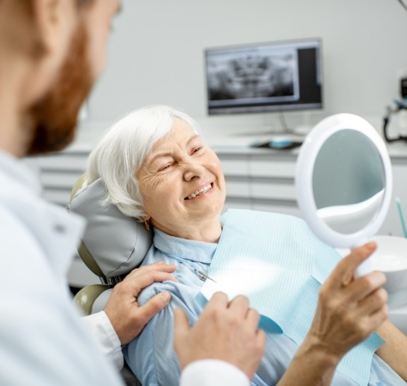Senior dental patient admiring her smile in a mirror
