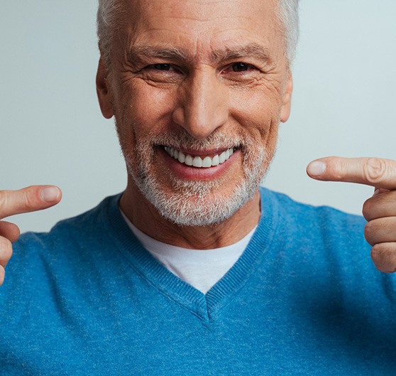 Man in blue shirt sitting outside clasping hands and smiling