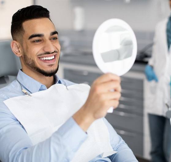 a patient checking his new veneers with a mirror