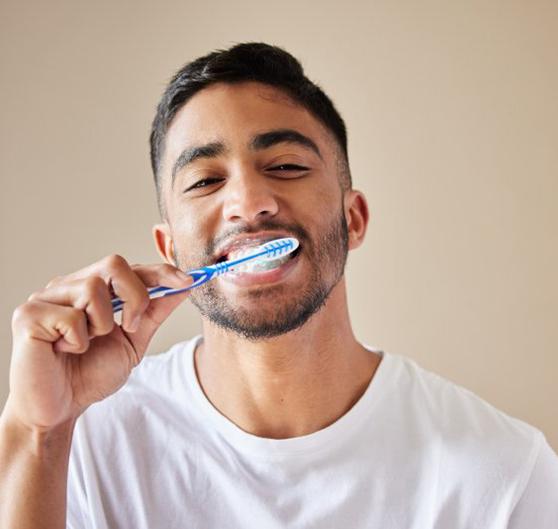 a man brushing his teeth to keep them bright