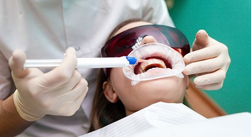 a patient receiving teeth whitening from her dentist